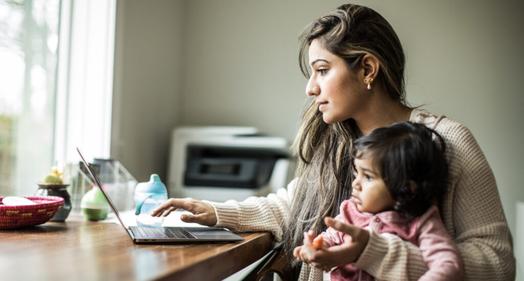 Depiction of mother multi-tasking with infant daughter in home office